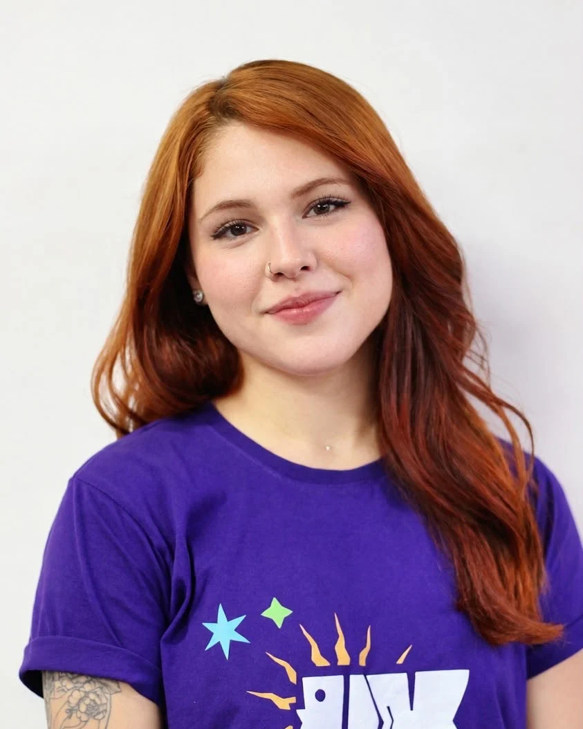 Vanessa Sousa sorrindo, com cabelo ruivo e camiseta roxa da UXFor.